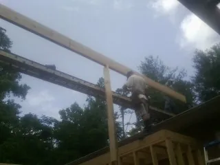 Carpenter setting a ridge beam over a new addition frame — Ice Dam Removal by Roofing Brothers in Bourbon