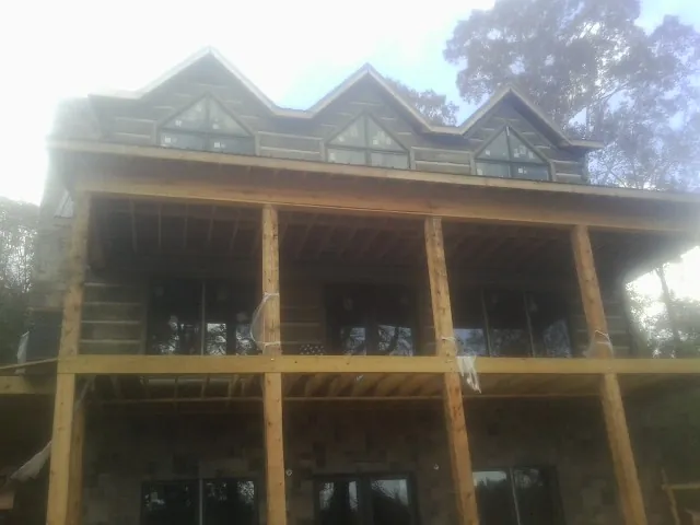 Dormers and porch framing on a large log home under construction — Roof Coating work by our crew in Bourbon