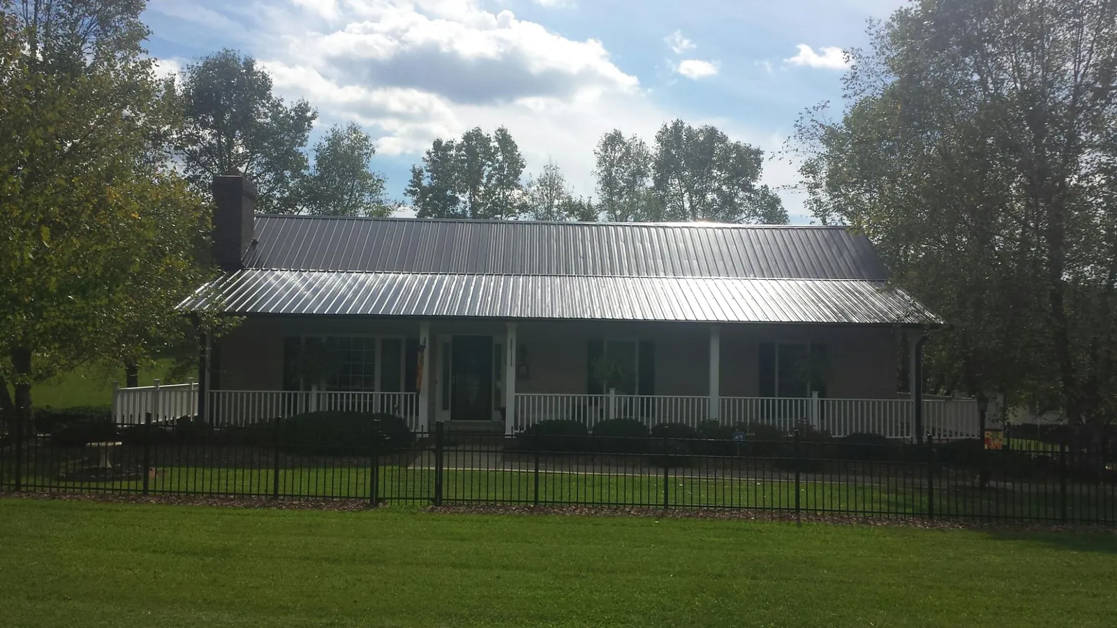 Gray metal roof on a brick ranch with a full width front porch — Gutter Guard Installation work by our crew in Bourbon